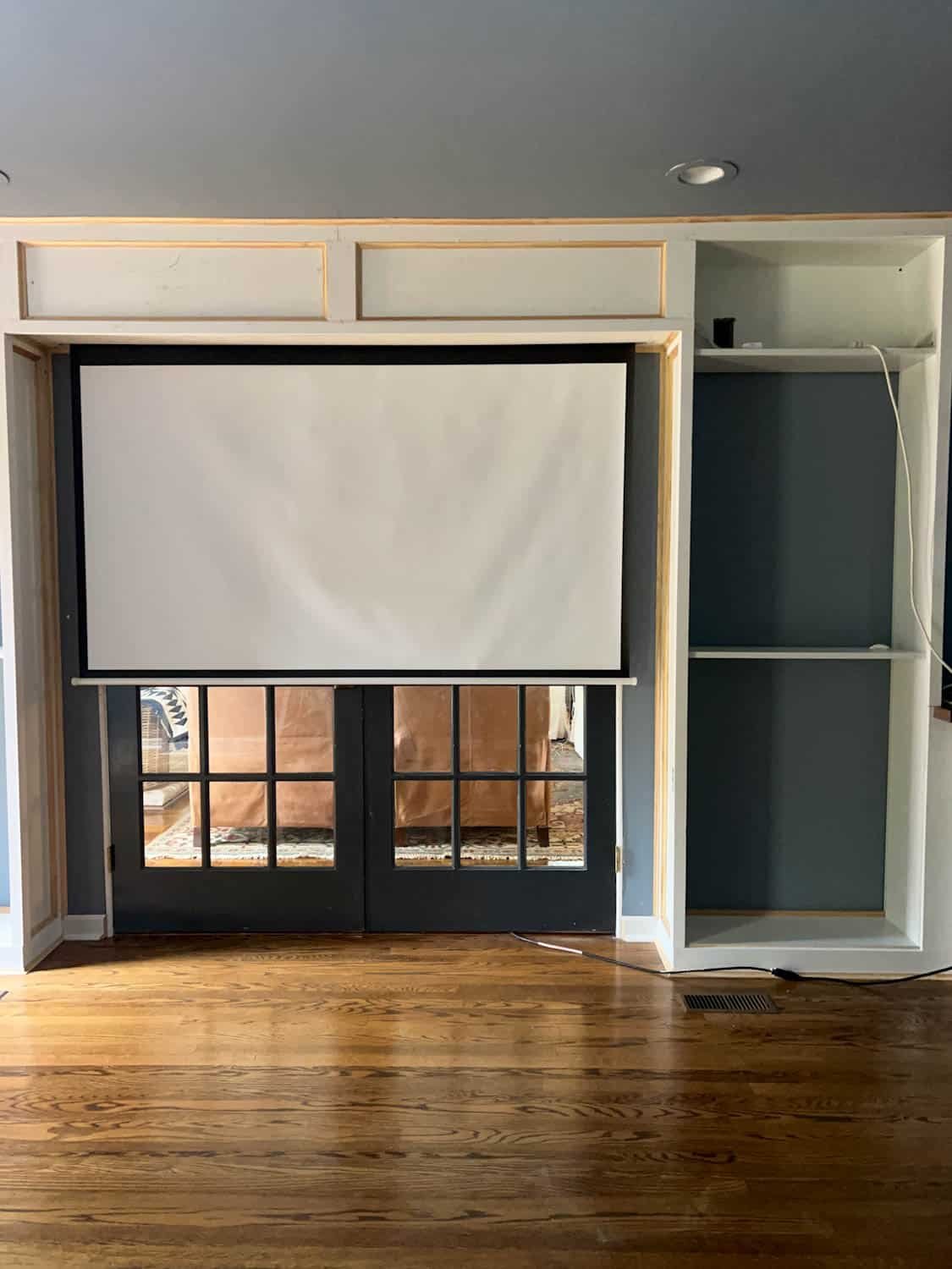 hidden projector screen between bookcases above French doors