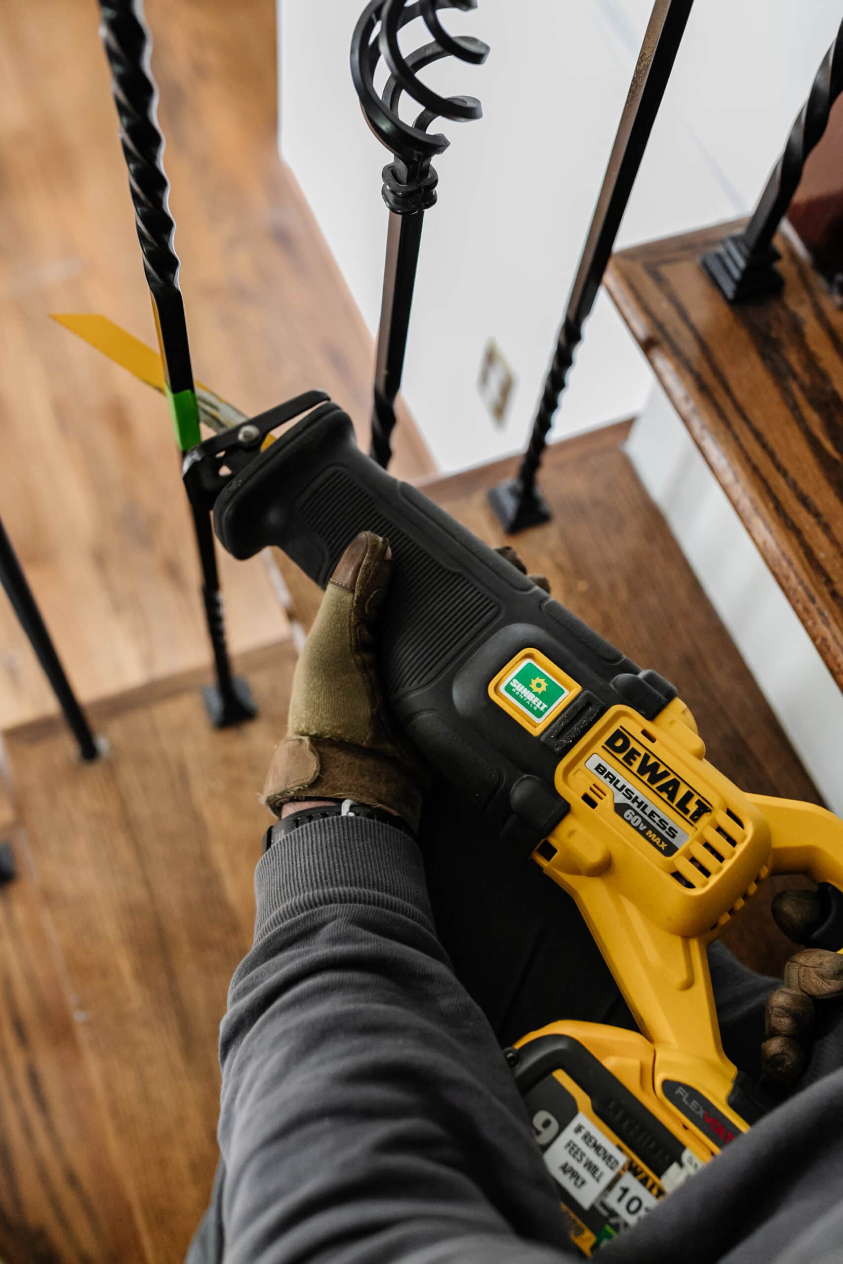 close up of cutting wrought iron stair balusters with a reciprocating saw