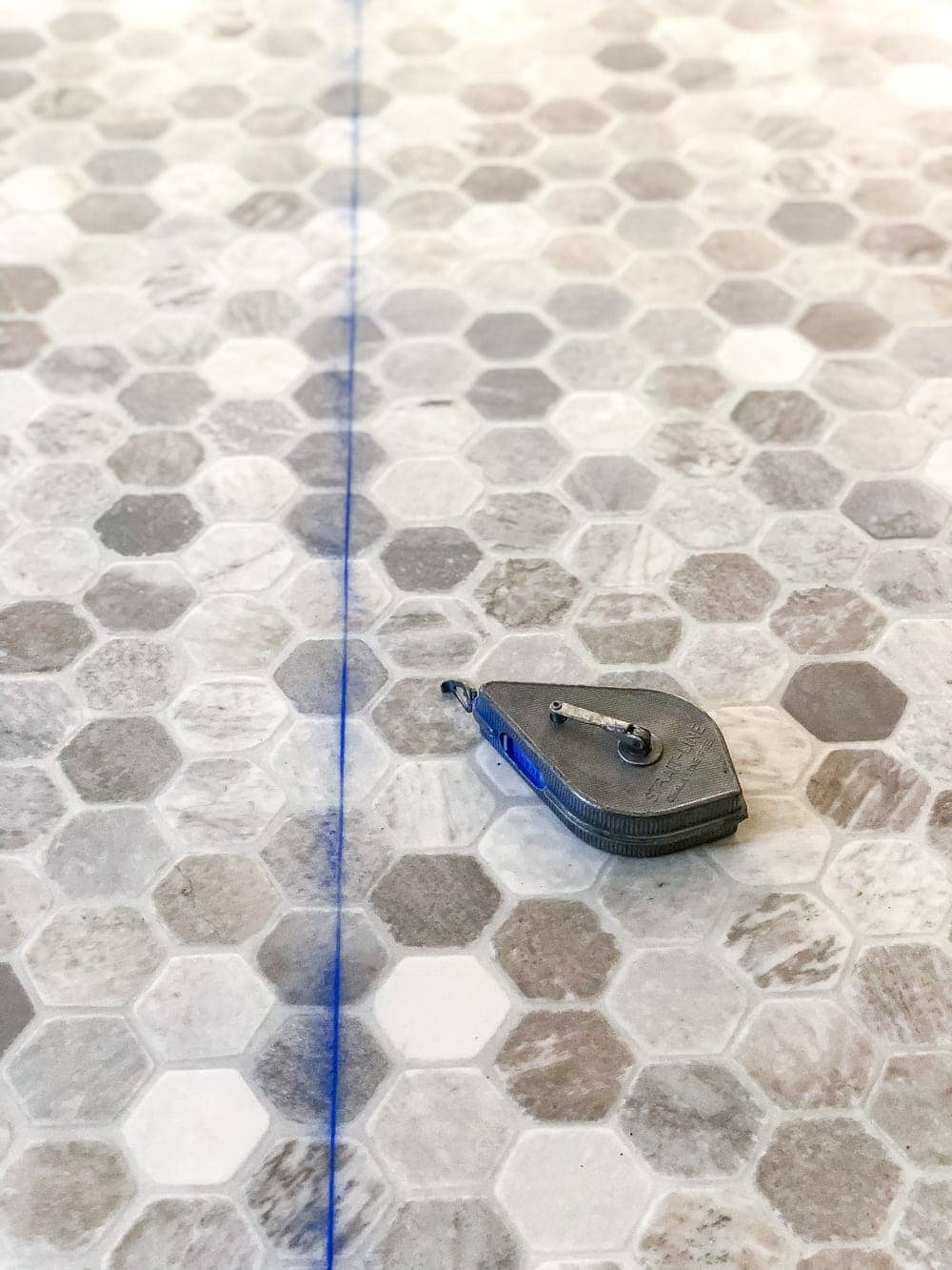 using a chalk line to cut straight lines between measurements on sheet vinyl