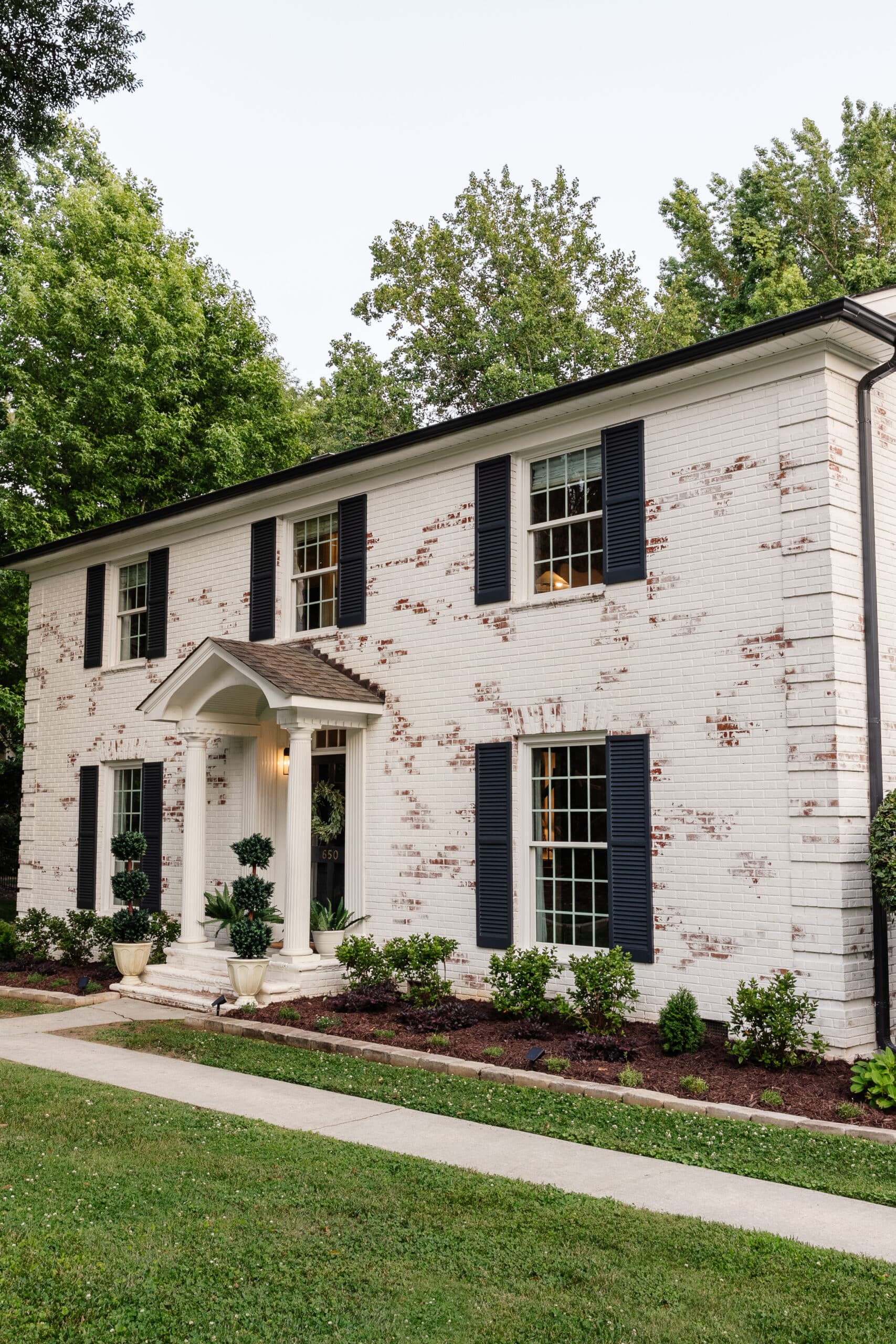 limewashed brick colonial house and flower beds