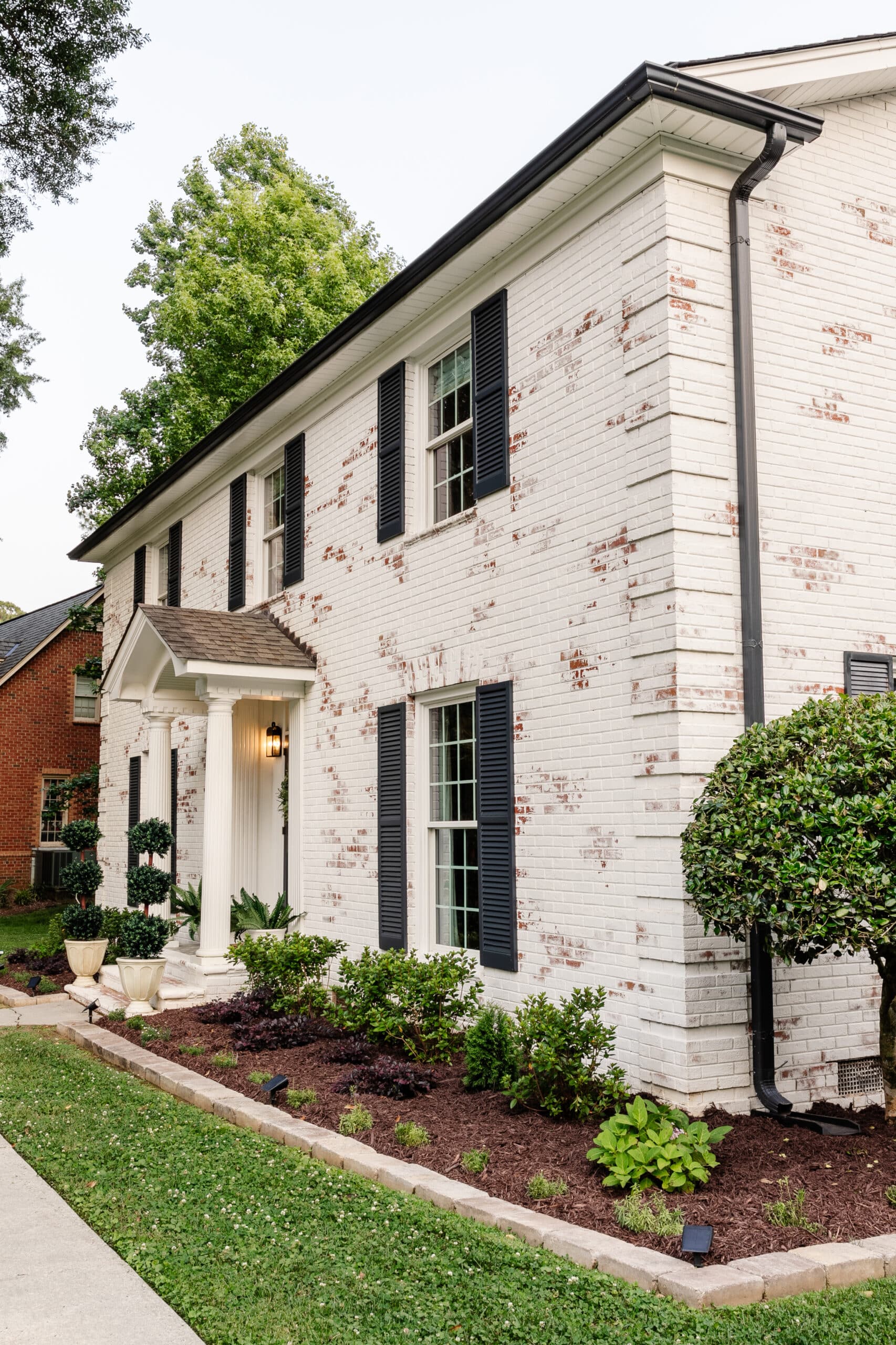 limewashed brick colonial house and flower beds