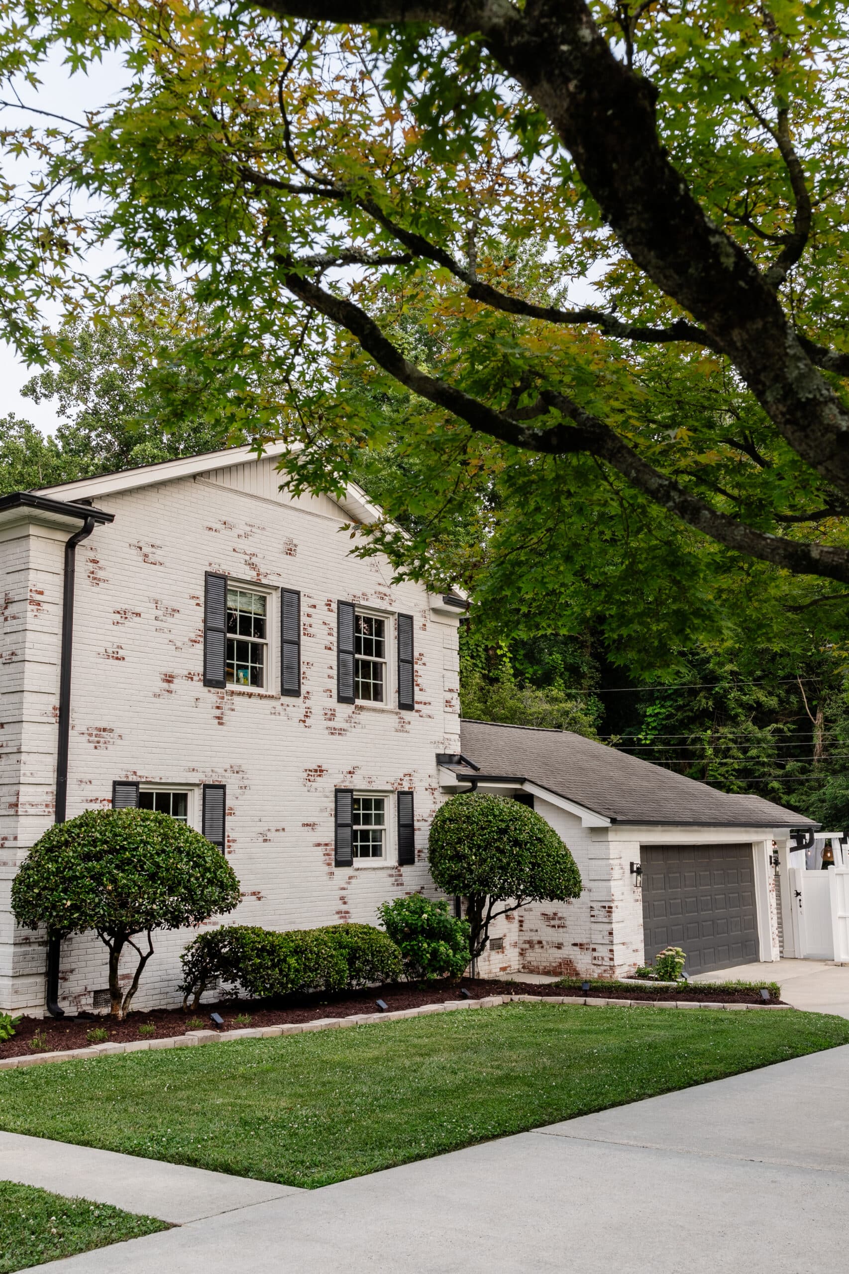 white limewashed brick with black gutters, black shutters, and black painted garage door