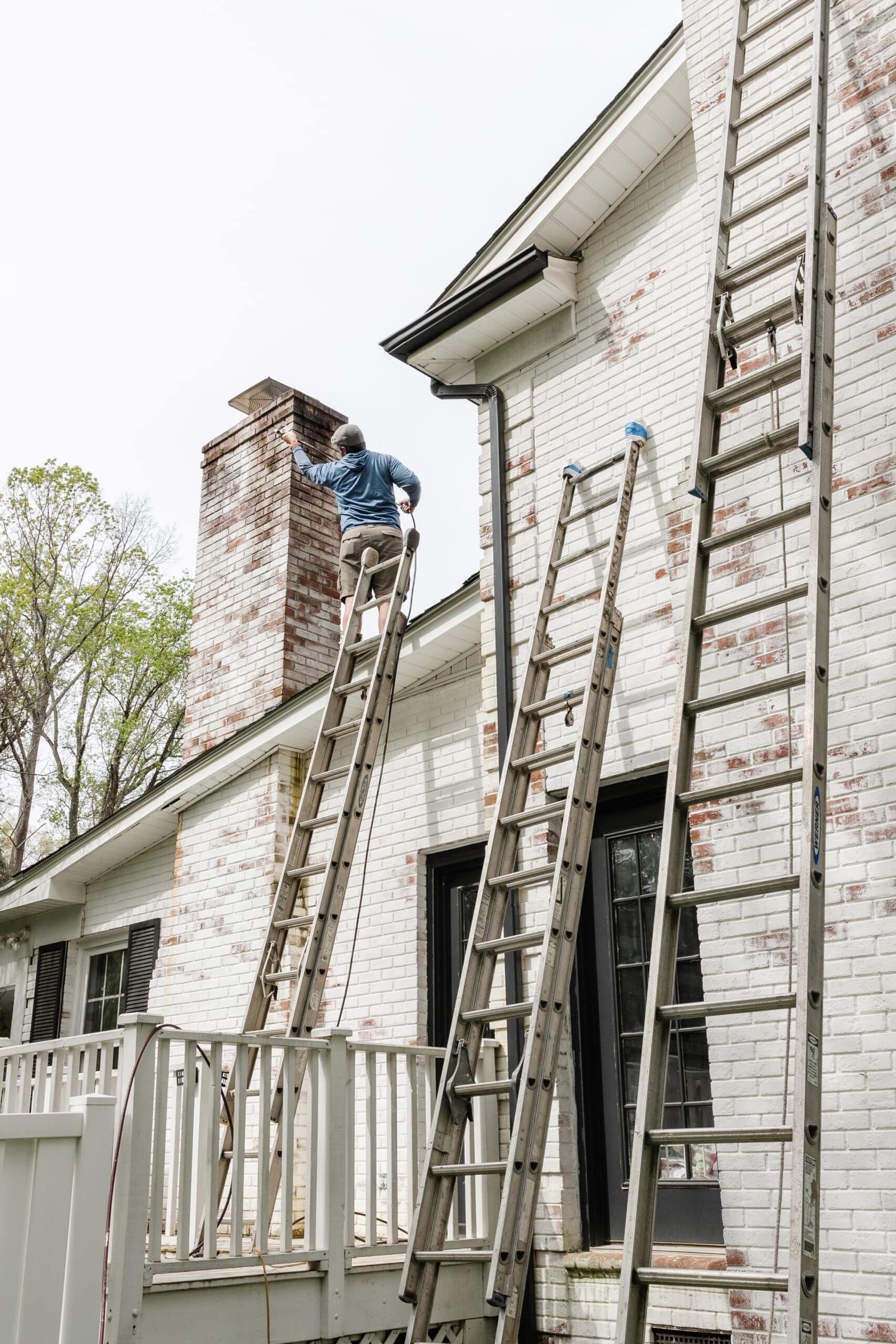 contractor on ladder cleaning limewashed chimney