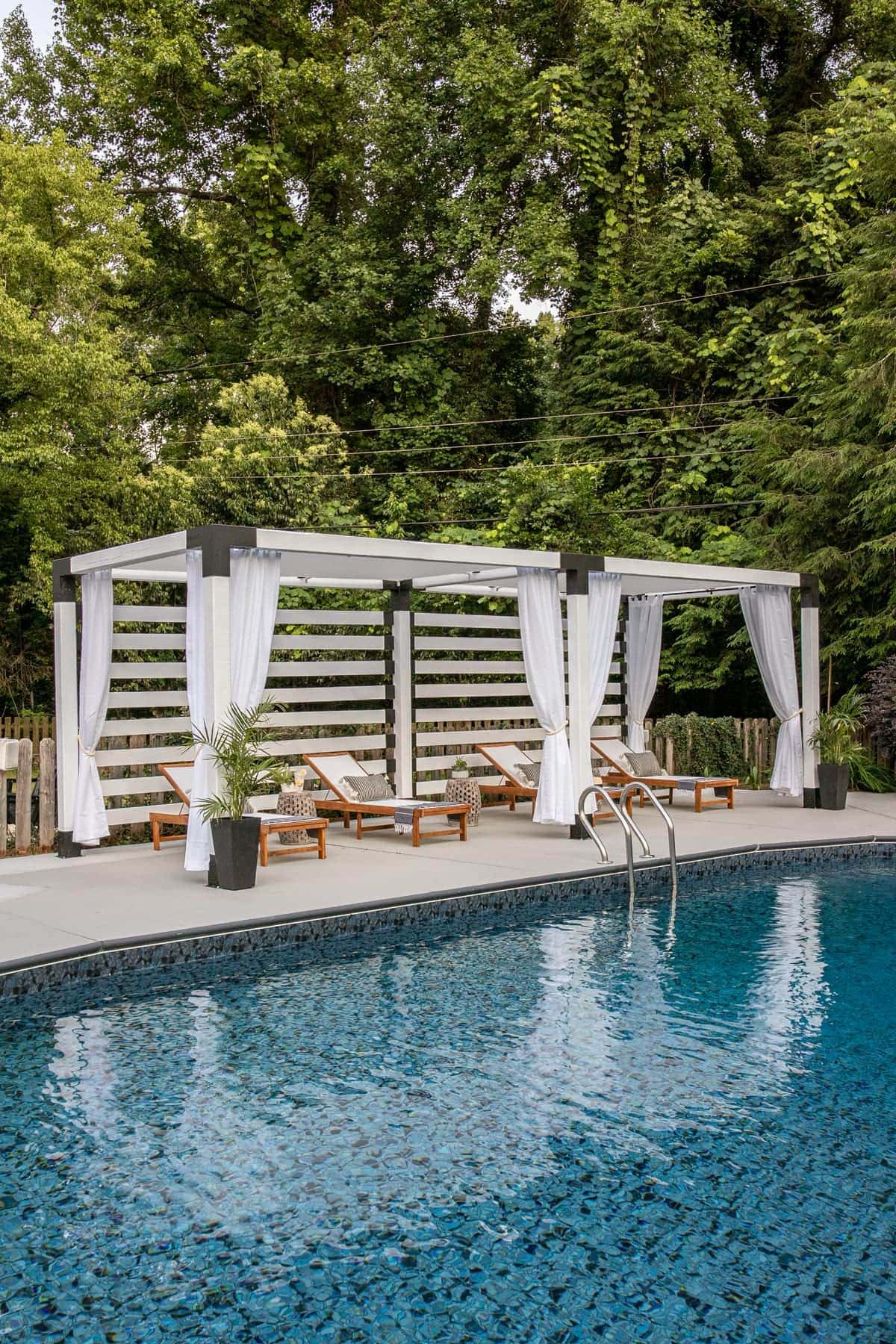 white DIY pergola cabana with outdoor curtains and lounge chairs