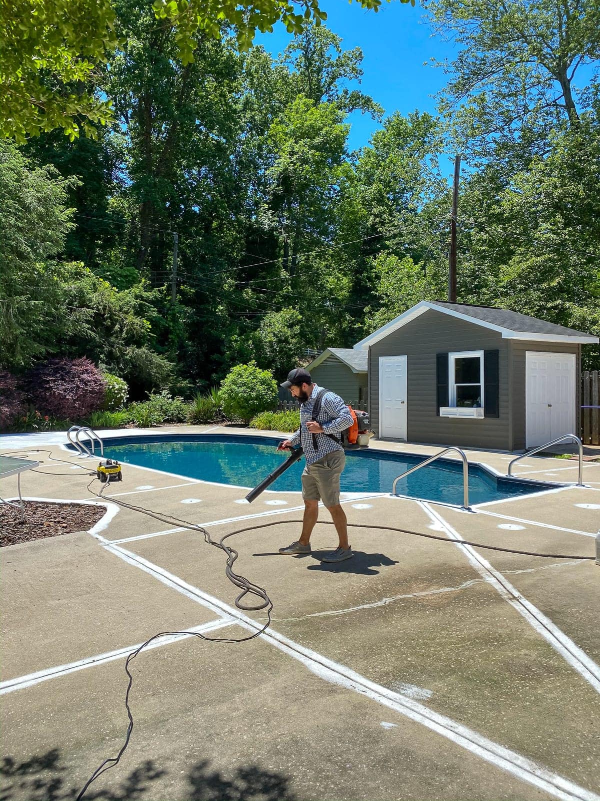 prepping a pool deck for painting by blowing off debris